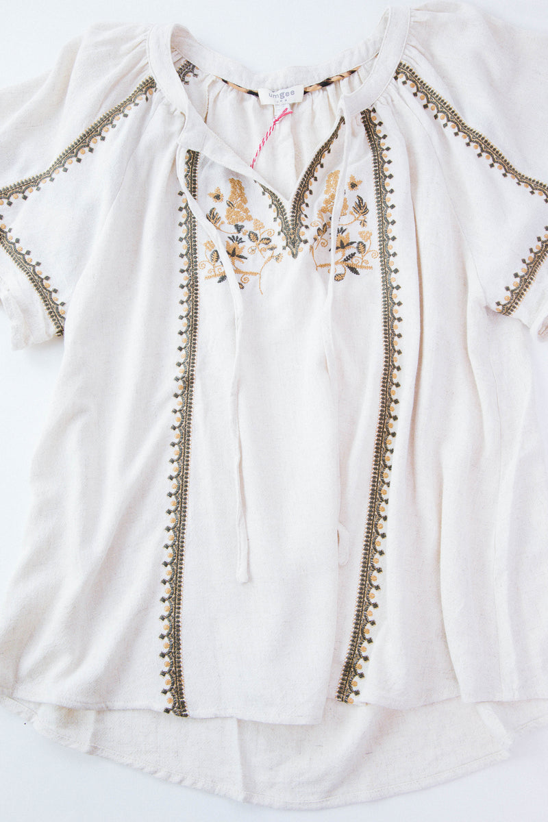 Detail shot of embroidered cream shirt on white background